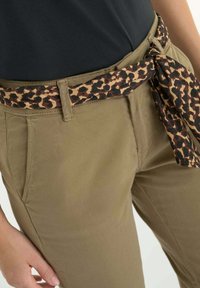 Pantalons kaki avec poches latérales, ornés d'une ceinture enroulée à motif léopard dans les tons marron et beige. Tissu lisse avec une coupe ajustée.
