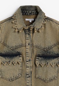 Jachetă din denim de un albastru estompat, cu guler ascuțit, margini în zigzag, două buzunare latente, și nasturi negri cu prindere. Finisaj texturat subtil.