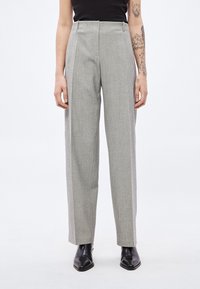 Hallid kõrge vöökohaga püksid tekstuurse mustriga, laia säärega ja voldid esiküljel. Sobitatud mustade pahkluu saapadega.