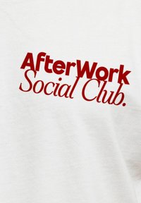 Weißes Sweatshirt mit auffälligem roten Text "AfterWork Social Club." auf der Vorderseite, mit glatter Textur und entspanntem Design.