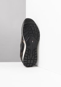Scarpa sportiva nera con suola in gomma testurizzata, caratterizzata da un distintivo motivo a macchie di leopardo sulla tomaia, lati rinforzati e tacco imbottito.