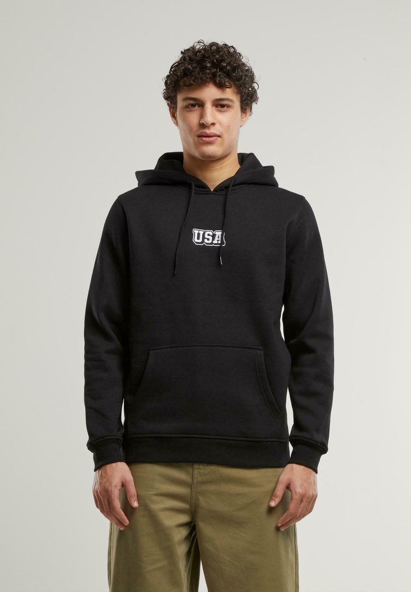 Čierny flísový hoodie s predným kloktacím vreckom, šnúrkami a bielym logom "USA" na hrudi. Tkanina je hladká a jemná.