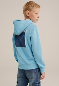 Vaaleansininen huppari, jossa etupussukka, taustapuolella tumma sininen graafinen kuvio ruutukuviolla ja teksti. Puuvillamateriaali, pehmeä tekstuuri.