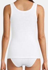 Top in cotone bianco a coste, con scollatura rotonda, dotato di spalline larghe e design aderente. Il tessuto appare liscio e leggero.