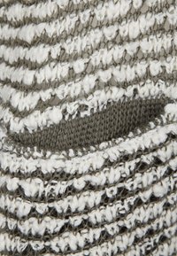 Stickad tyg i grått och vitt, med ett strukturerat mönster av öglor. Materialet verkar mjukt och löst vävt.