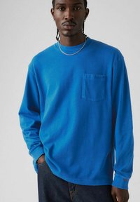 Long-sleeve blue cotton t-shirt with a round neck and chest pocket. Features a relaxed fit and subtle Levi's logo on the pocket.