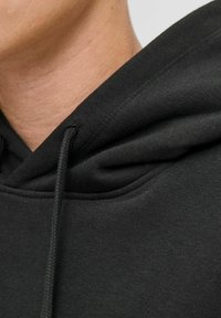 Sort hættetrøje med snor, der har en tekstureret stof og et close-up billede af halsudskæringen og søm detaljerne på hætten.