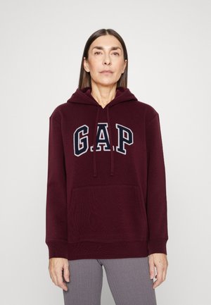 Burgunderfarget hettegenser med frontlomme og marineblå GAP-logo. Myk tekstur med snorhette, ribbestrikkede mansjetter og hem. Normal passform.