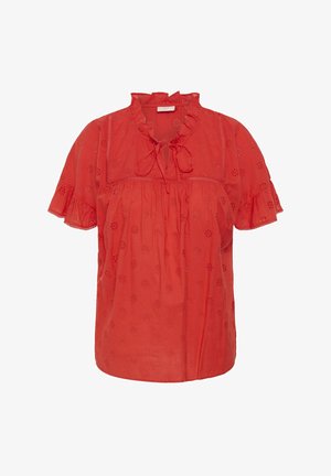 Blouse rouge à manches courtes avec motif floral en ajouré, encolure à volants, détail noué à l'avant et bords de manches volantés.