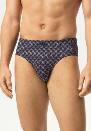 Man draagt marineblauwe slip met een klein wit en rood fietsje patroon, staand tegen een effen lichte achtergrond.