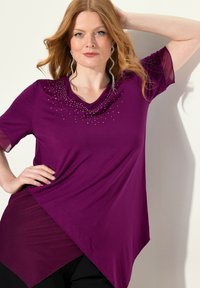 Paarse top met korte mouwen, featuring een cowl halslijn, asymmetrische zoom en strass-details aan de voorkant. Gladde stof, sheer mouwaccenten.