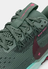 Nike Pegasus Trail 5 kingad, millel on roheline võrkmaterjalist pealispind, tekstuuriga paelad, lillad ja roosad aktsendid ning piparmündiroheline tall.