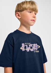 Marinblå bomullst-shirt med korta ärmar, med ett grafiskt tryck och texten "serve the game" i lila och krämfärger.