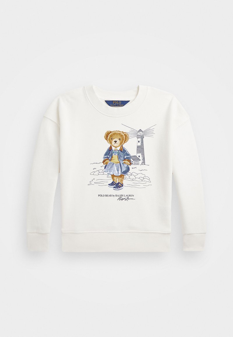 Vit sweatshirt med en grafik av en björn i denimjacka och sneakers, med en bakgrund av ett fyrtorn och texten "POLO BEAR by RALPH LAUREN."