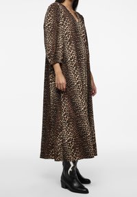 Vestido maxi de estampado de leopardo con escote en V y mangas tres cuartos, hecho de una tela suave, combinado con botas vaqueras negras.