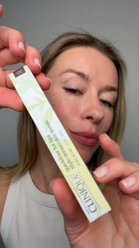 Femme tenant un packaging Clinique quickliner pour les lèvres étiqueté 21 Black Honey, gros plan sur le visage et le produit.
