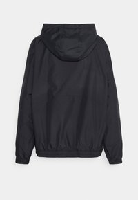 Svart huva jacka i ett lätt, vattenavvisande material. Har elastiska ärmslut och nederkant, vilket ger en enkel, strömlinjeformad design.