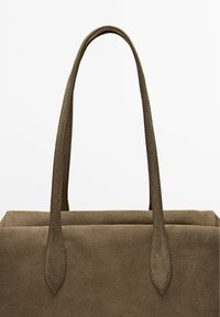 Borsa a tote in suede marrone con due manici allungati, caratterizzata da una texture liscia e dettagli cuciti, che mostra un design minimalista.