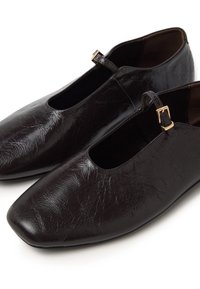 Dark brown shoes made of textured leather, featuring square toes, open sides, and a small gold-tone buckle detail on the strap.