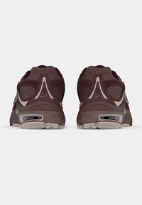 Zapatillas deportivas marrones con una parte superior de malla texturizada, suela acolchada y acentos en beige contrastante. Vista trasera que resalta la forma única y los detalles.