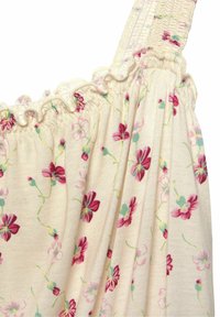 Kremowa tkanina z marszczoną falbaną i paskiem na ramię, w nadruk małych różowych i czerwonych kwiatów z zielonymi łodygami.
