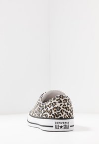 Sapatilha em tela de padrão de leopardo com sola de borracha preta, logotipo na parte traseira "CONVERSE ALL STAR" e colarinho elástico para fácil colocação.