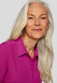 Fuchsia button-up shirt with a pointed collar and a smooth texture, worn by a woman with long, straight, silver hair.