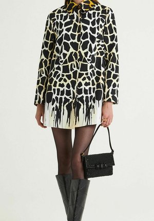 Giraffe-patterned shirt dress with a black and yellow collar, paired with knee-high black textured boots and a small beaded black handbag.