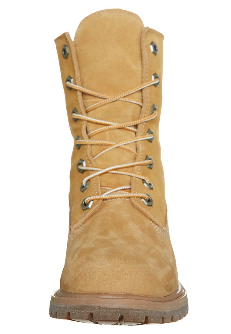Bottine en suède tan avec bout rond, œillets en métal et lacets beiges. Surface texturée et semelle en caoutchouc avec un motif de relief prononcé.