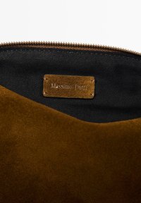 Interno di borsa in suede marrone con rivestimento in tessuto scuro; presenta un piccolo etichetta rettangolare beige embossata con "Massimo Dutti". Chiusura con zip.