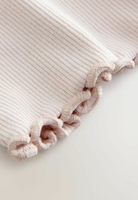 Rippstoff in sanftem Rosa mit einem Rüschensaum. Die Textur ist glatt mit subtilen Streifen, die das zarte Erscheinungsbild unterstreichen.