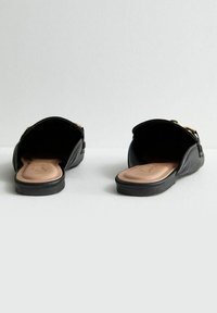 Černé pantofle na klínu s hladkým koženým svrškem, otevřeným zadním dílem a béžovou stélkou. Mají zlatý akcent u pásku. Oheb sole z gumy.