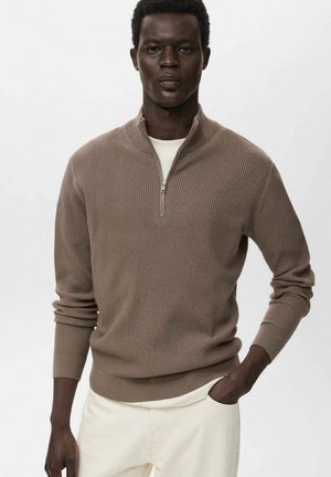Brown ribbed knit pullover with a high zipper collar, soft texture, long sleeves, and worn over a white crew neck shirt.