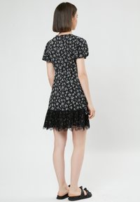 Vestido negro con flores que presenta mangas cortas abullonadas, un borde de encaje en el dobladillo y un cuerpo ajustado con un sutil patrón floral en toda su superficie.