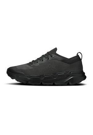 Chaussure de sport noire avec bout texturé, semelle rembourrée et design à lacets, avec languette au talon et logo latéral discret.