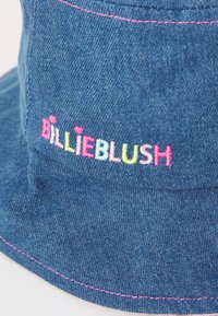 Chapéu bucket de denim azul com costuras rosas e o texto bordado "BILLIEBLUSH" em letras multicoloridas. O texto inclui acentos em forma de coração.