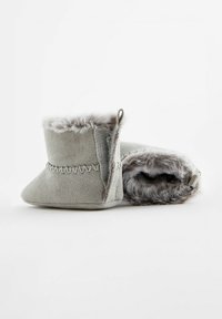 Bottes en suede grises avec une bordure en fourrure en haut, présentant des détails cousus et une doublure douce. Bout arrondi et un petit tirant pour un enfilage facile.