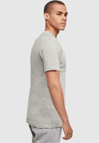 Camiseta de manga corta gris claro hecha de algodón suave, con un cuello redondo y un dobladillo recto. Diseño minimalista sin gráficos visibles.
