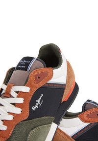 Mångfärgade sneakers som har en blandning av brun mocka, svart och vitt syntetmaterial. Inkluderar vita snören, logodetaljer och texturerade sulor.