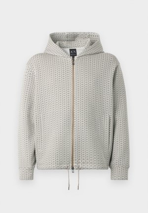 Casaco com capuz e fecho éclair em cinza claro com um padrão geométrico em cinza mais escuro. Apresenta um cordão na bainha e punhos canelados.