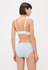 White lace bralette with adjustable straps and gold hardware, paired with light blue high-waisted briefs featuring thin white stripes.