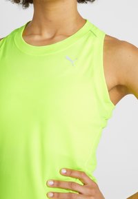 Neonově zelený sportovní top s kulatým výstřihem, žebrovanou texturou a malým bílým logem Puma na hrudi.