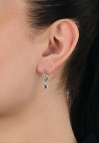 Orecchini a cerchio in argento con un piccolo pendente in pietra verde, caratterizzati da una finitura lucida e da un design semplice e minimalista.