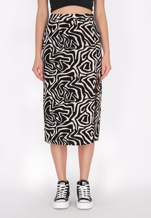 Fustă midi dreaptă, neagră și bej, cu model abstract și șliț lateral, purtată cu top scurt negru și adidași alb-negru.