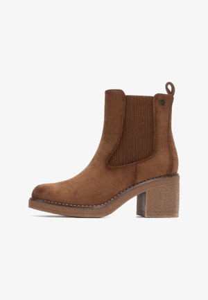 Stivaletto in suede marrone con pannelli laterali elasticizzati a coste, punta rotonda e tacco spesso texturizzato. Presenta una piccola linguetta sul retro.