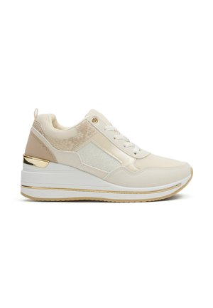 Zapatilla deportiva para mujer en beige y blanco con paneles de malla y textura, cordones blancos, suela gruesa con plataforma y detalles en dorado.