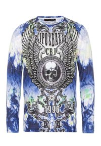 Langarmshirt im blau-weißem Batikmuster mit schwarzem Grafikdruck, der Flügel, einen Totenschädel und die Jahreszahl 1996 in Weiß zeigt.