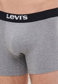 Graue Baumwoll-Boxershorts mit einem schwarzen Bündchen, das mit weißem "Levi's"-Branding versehen ist. Weiche Textur und enge Passform, die für Komfort sorgt.