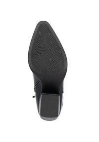 Zapato de tacón negro con punta afilada. Suela de goma texturizada con patrones geométricos y un tacón ligeramente elevado. Material superior suave.