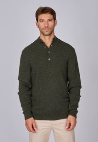 Pull en maille texturée vert foncé avec un col montant, fermeture à trois boutons à l'avant et manches longues. La couleur comprend des petites touches de jaune.
